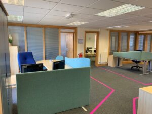 A training centre of excellence with grey flooring, pink walkways, green screens and blue chairs.